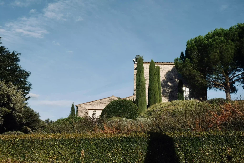Jardin arboré dans un mas provençal, avec des cyprès, et une haie de buis