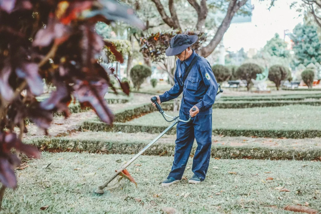 Homme qui à une débroussailleuse qui cale à chaud, dans un jardin