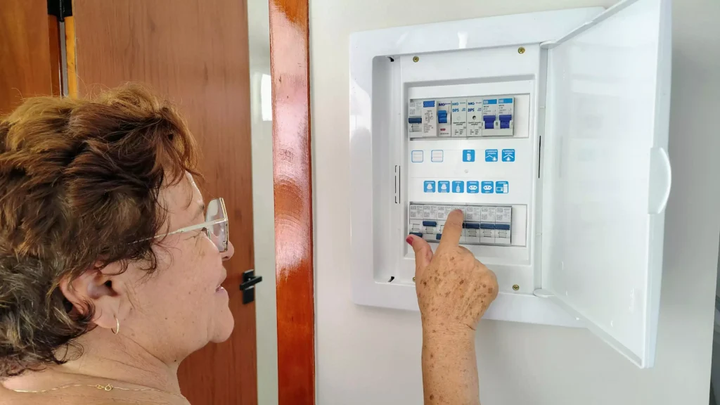 femme âgée regardant un tableau électrique pour vérifier si le disjoncteur est ok